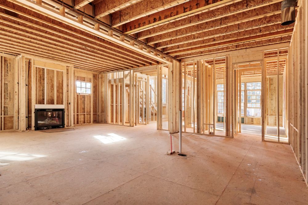 Unfinished wood-framed house interior with exposed beams, studs, and a fireplace