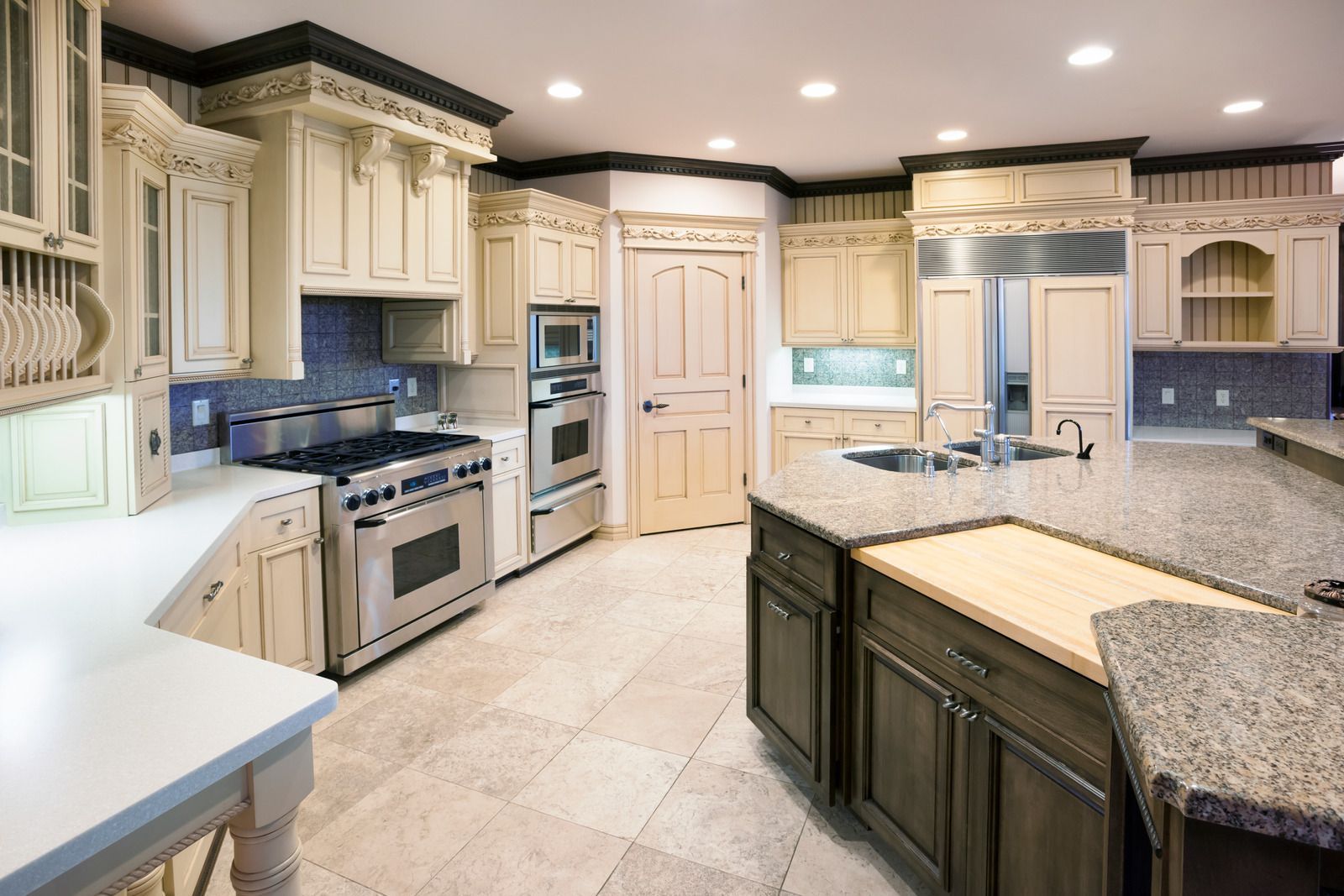 Bright modern kitchen with cream cabinets, granite countertops, stainless stove, and large island