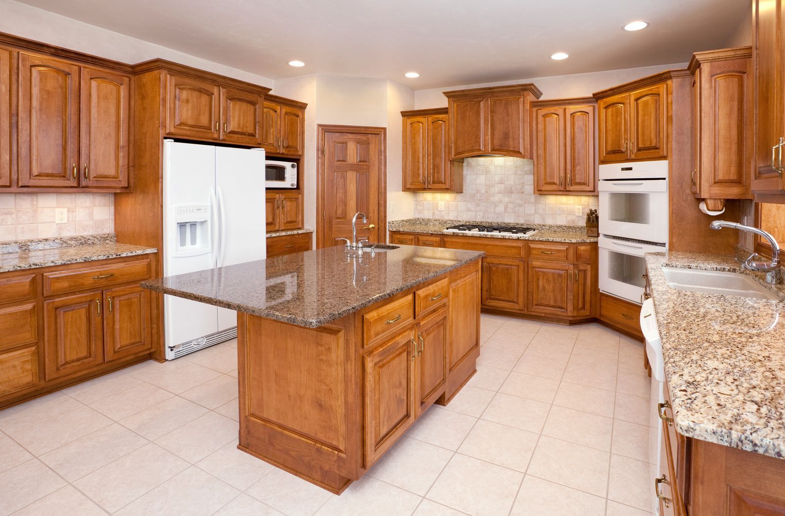 Spacious modern kitchen with wood cabinets, granite countertops, white appliances, and a central island.