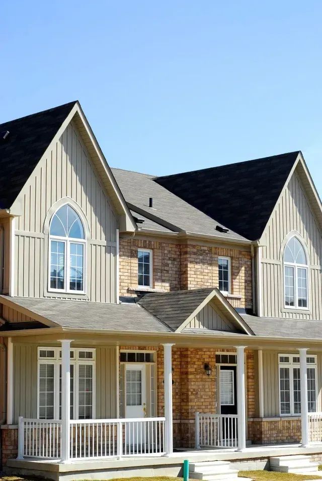 Two-story suburban house with brick and beige siding, arched windows, and a covered front porch
