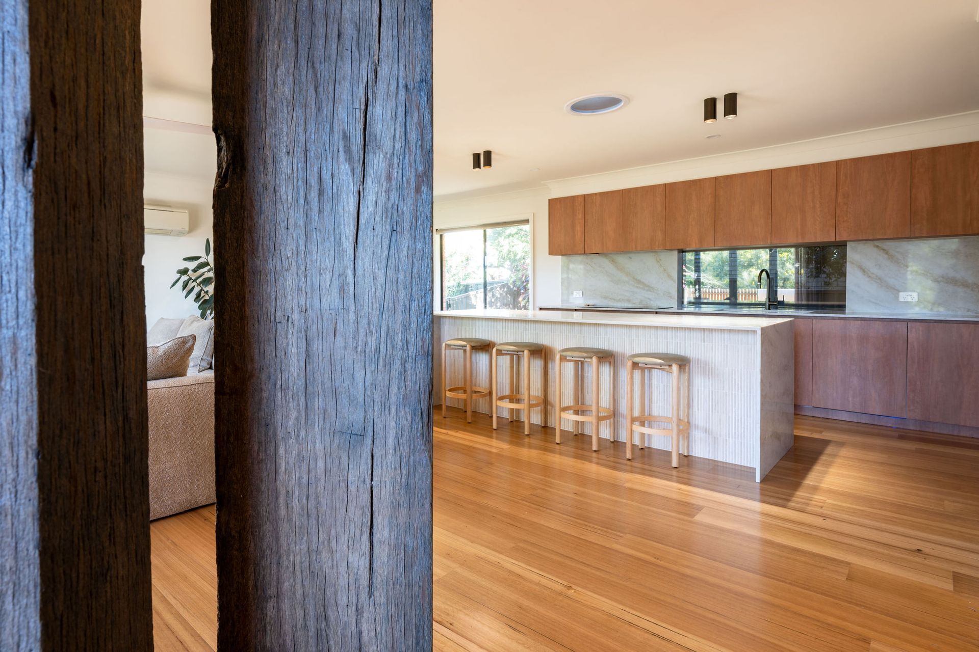 Modern Kitchen With Red Oven, Wood Cabinets, and White Countertops Island With Stools, Large Window — Flow Kitchens in Taree South, NSW