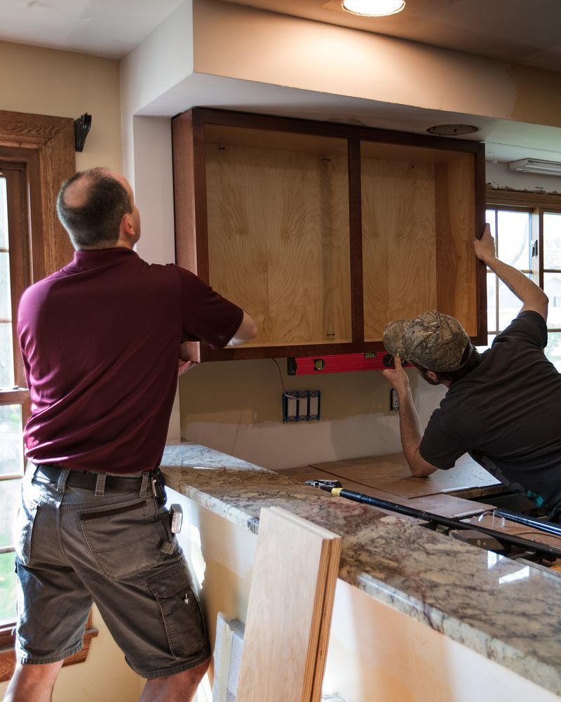 Two Men Are Measuring a Cabinet in a Kitchen — Flow Kitchens in Taree South, NSW