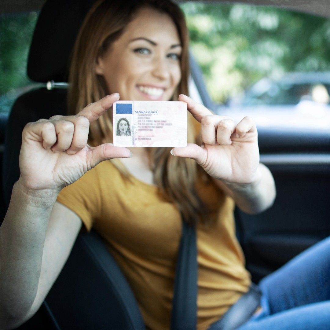 A woman in a car is holding up her id card