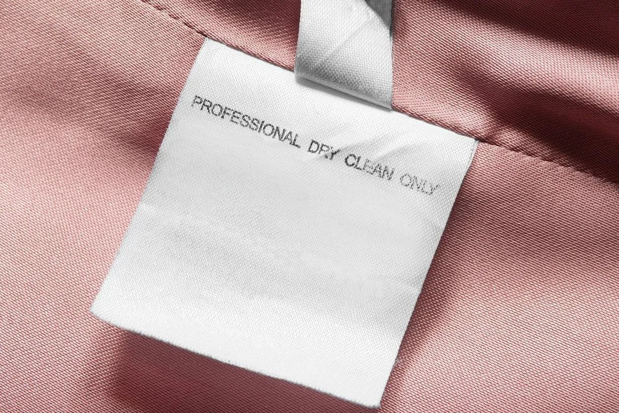 White clothing tag on pink fabric; reads 