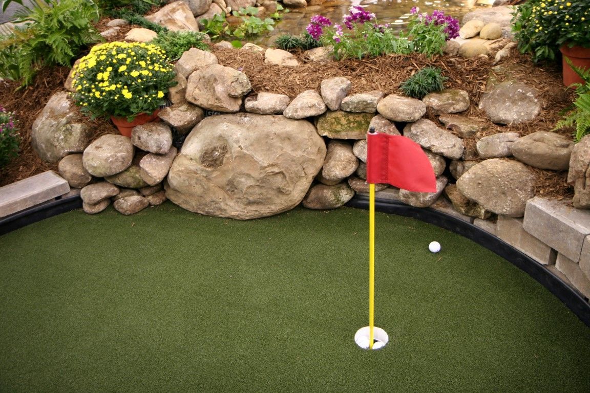 Golfer putting on a pristine backyard synthetic green.