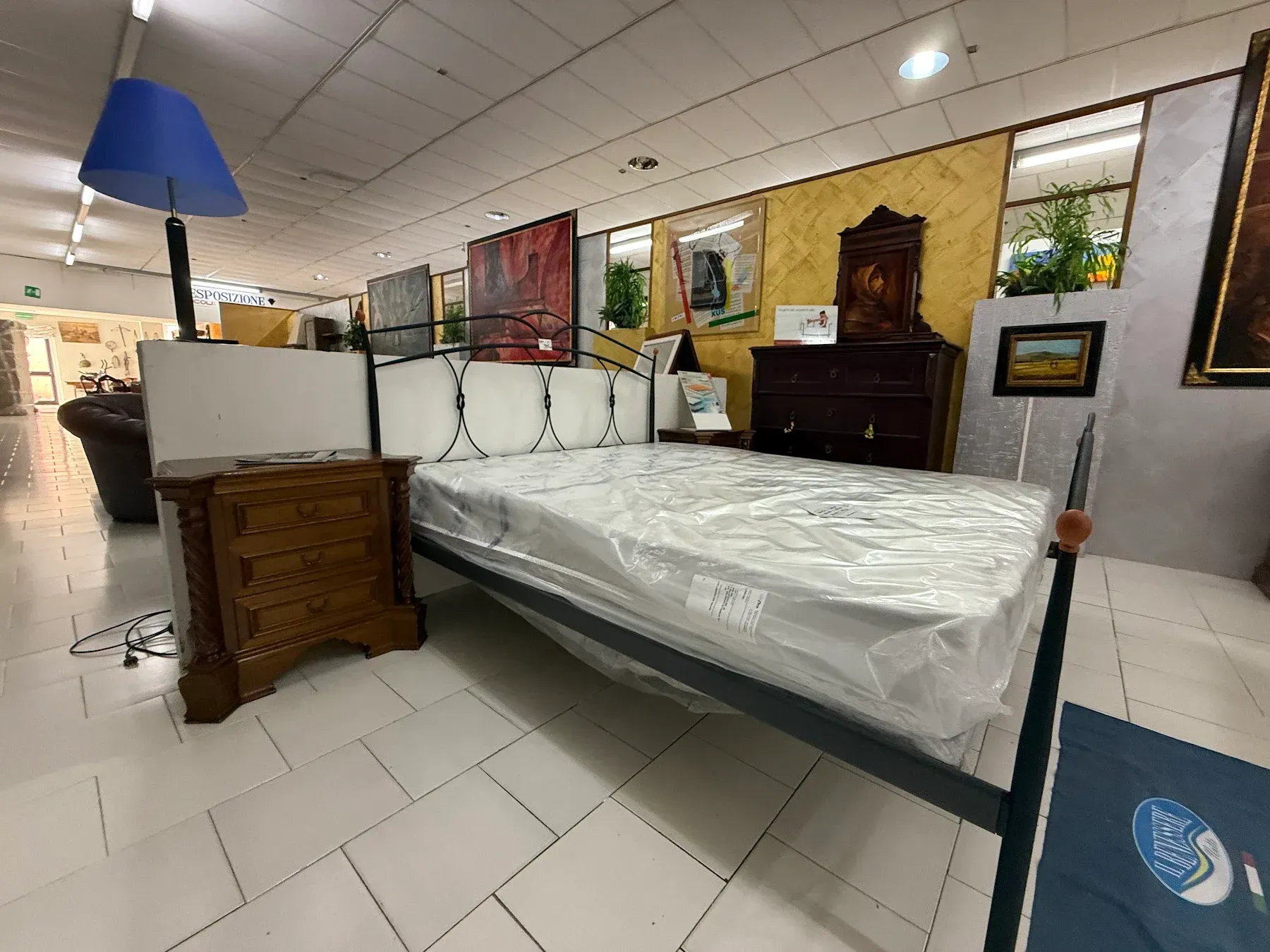 Struttura letto in metallo nero con testiera curva e materasso bianco su sfondo bianco.