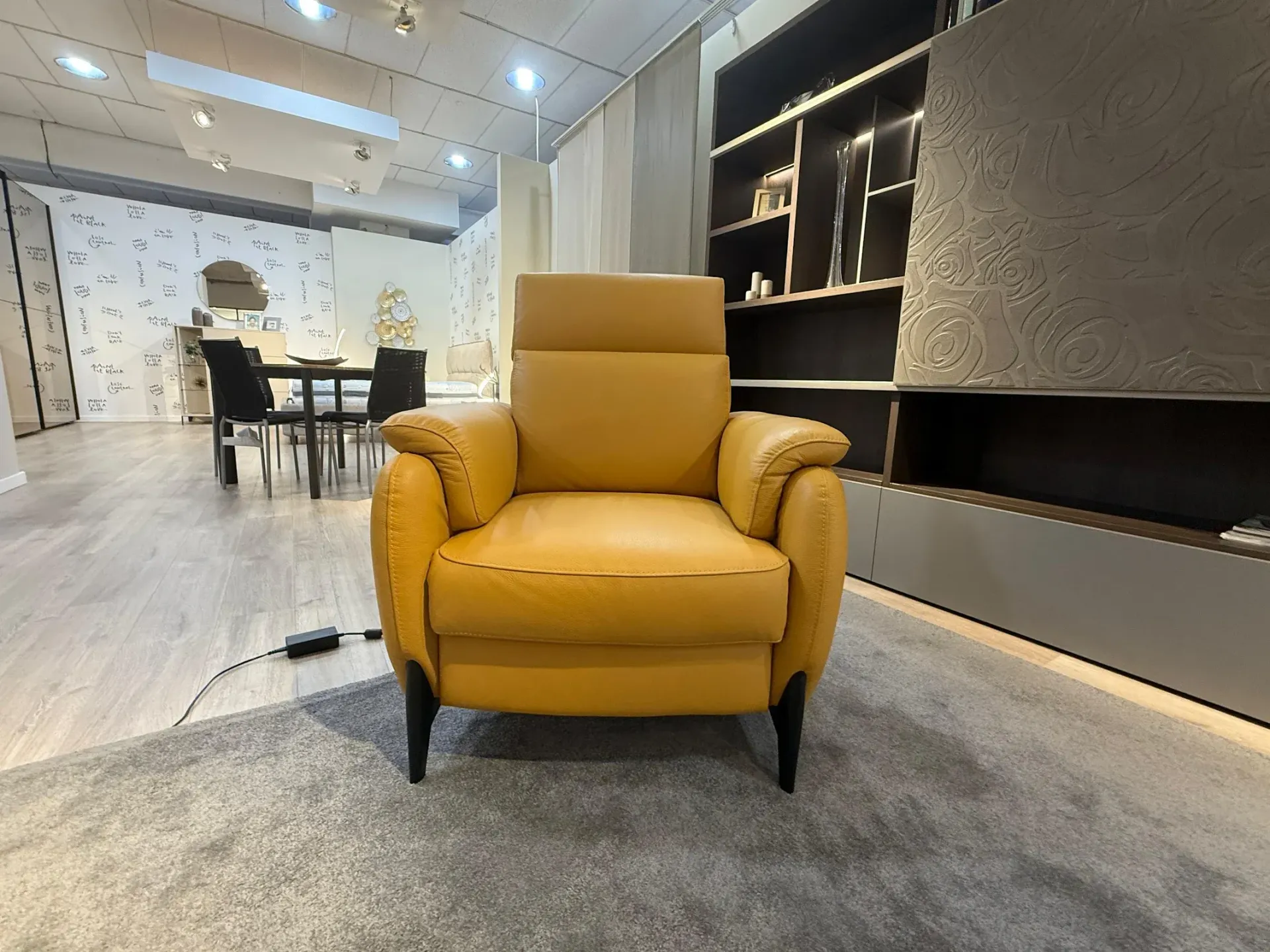 Poltrona color giallo senape con braccioli arrotondati e gambe nere su sfondo bianco.