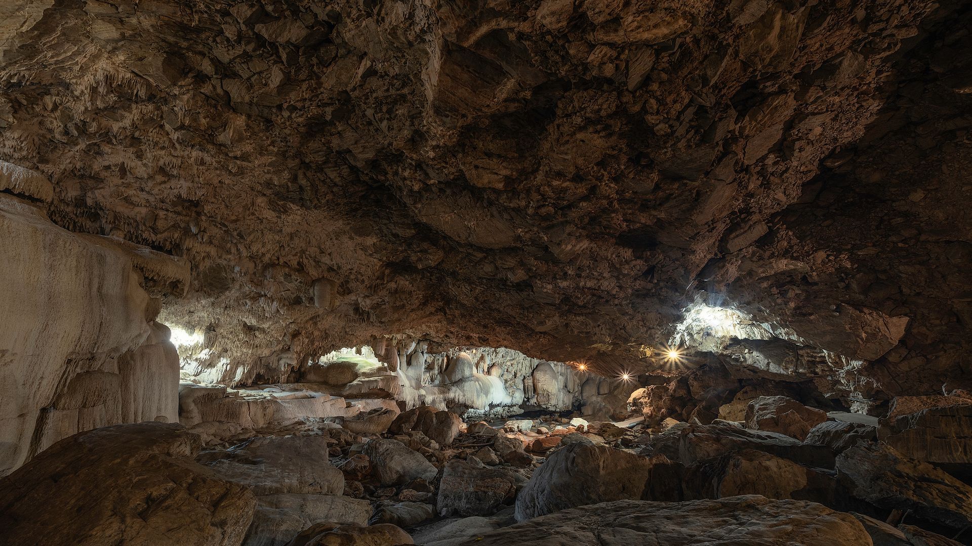 A large cave filled with rocks and a light coming out of the ceiling.