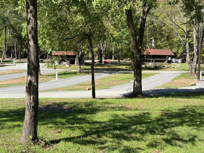 A park with a lot of trees and grass and a house in the background.