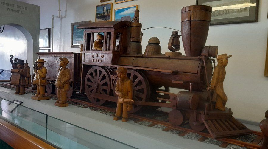 A wooden train with cowboys on it is on display in a museum.
