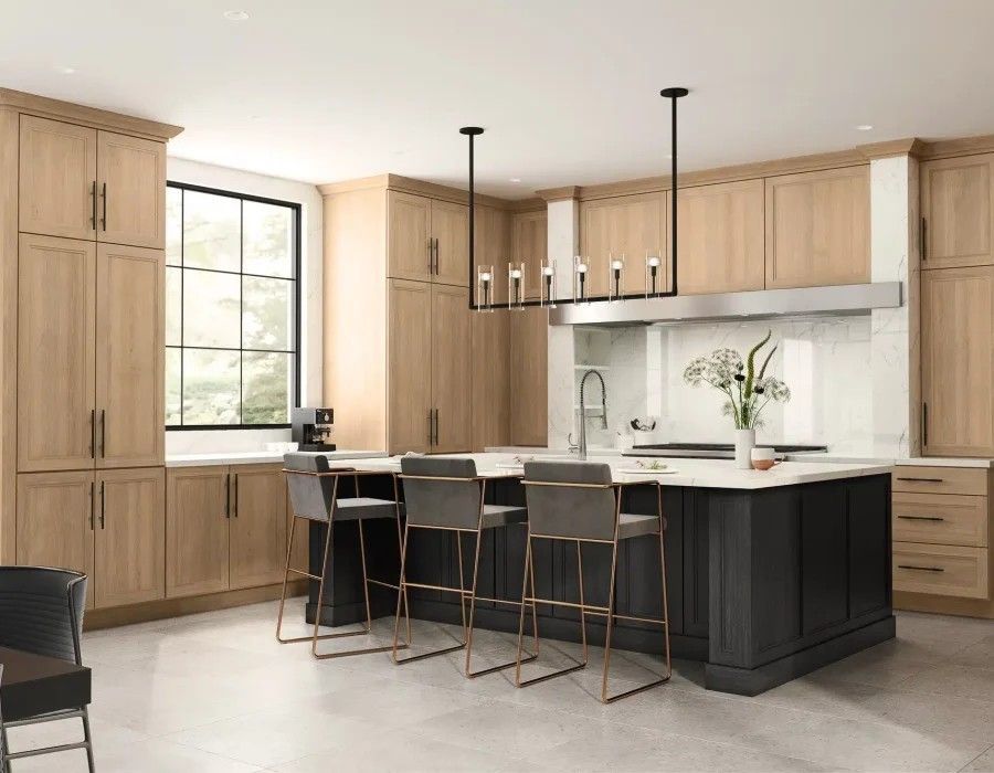Modern kitchen with light wood cabinets, black island, and three bar stools by a bright window
