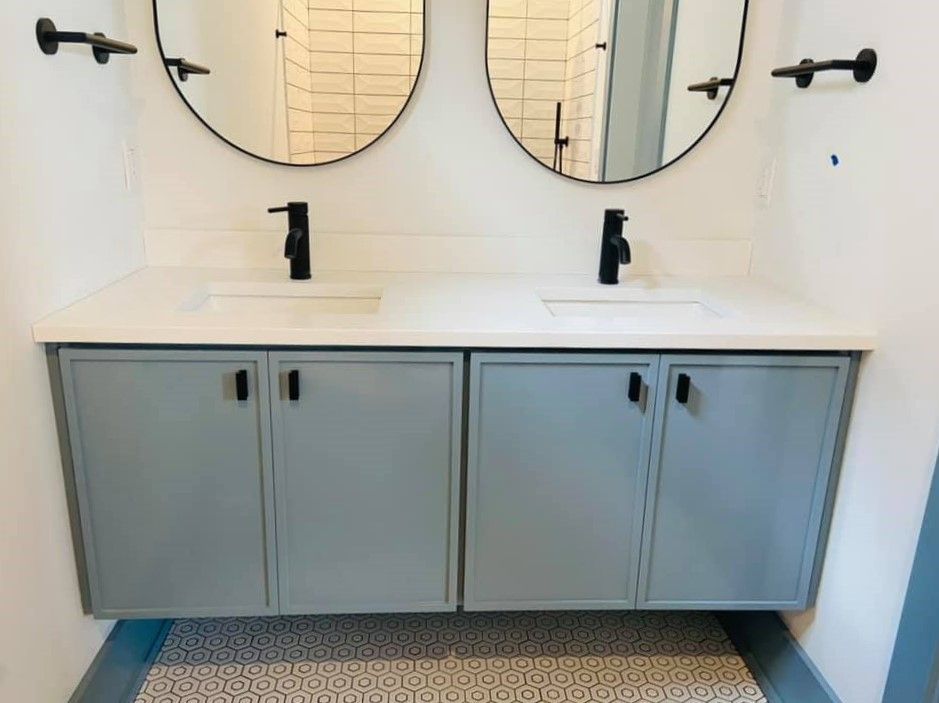 Modern bathroom vanity with double sinks, round mirrors, black faucets, and gray cabinet doors