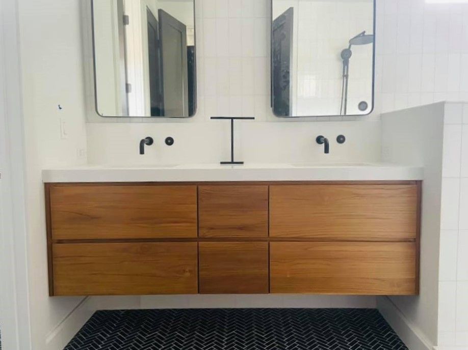 Modern bathroom vanity with double mirrors, black faucets, and a wood cabinet over a patterned black rug