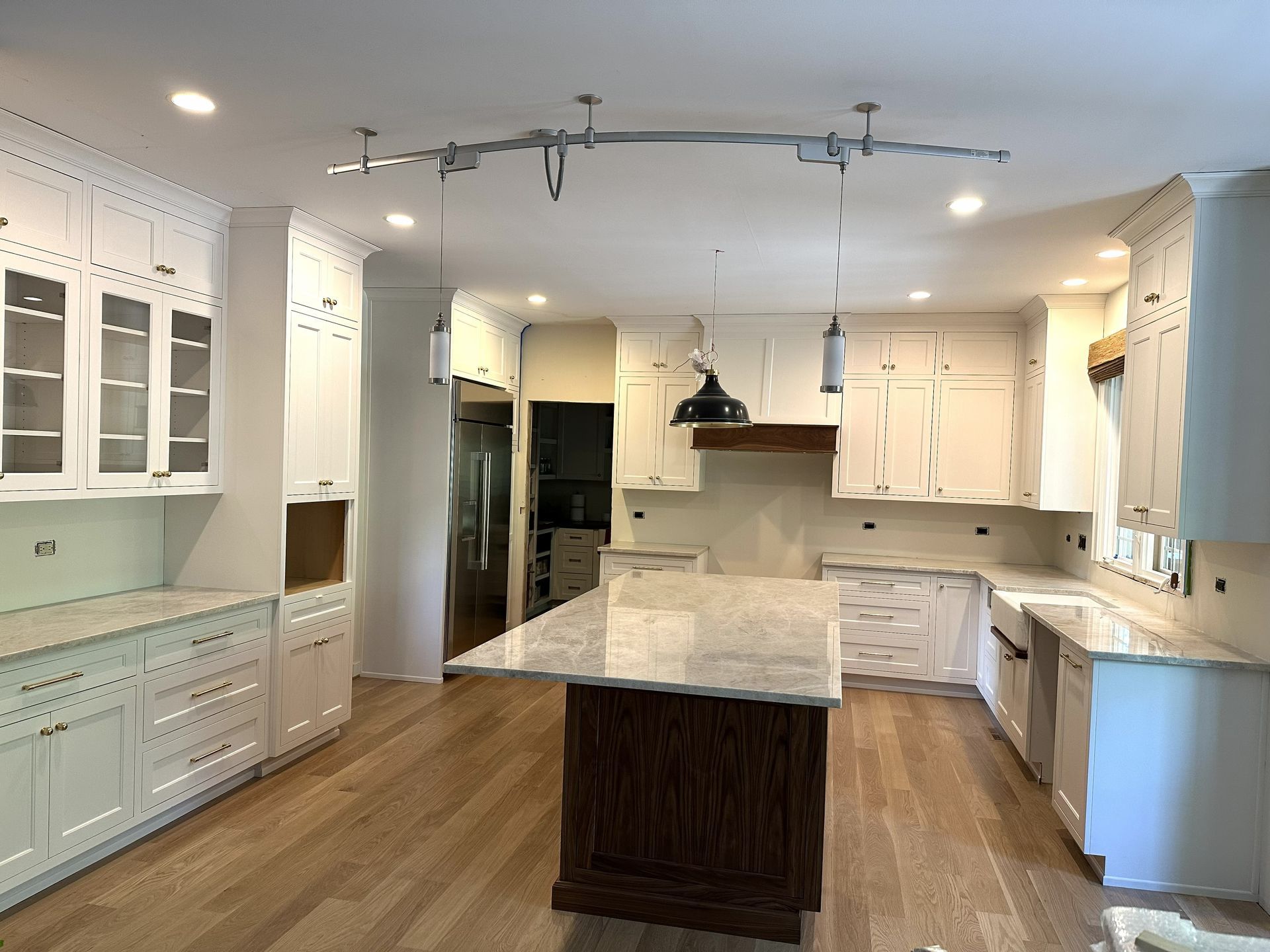 Modern kitchen with white cabinets, marble island, hardwood floors, and pendant lights