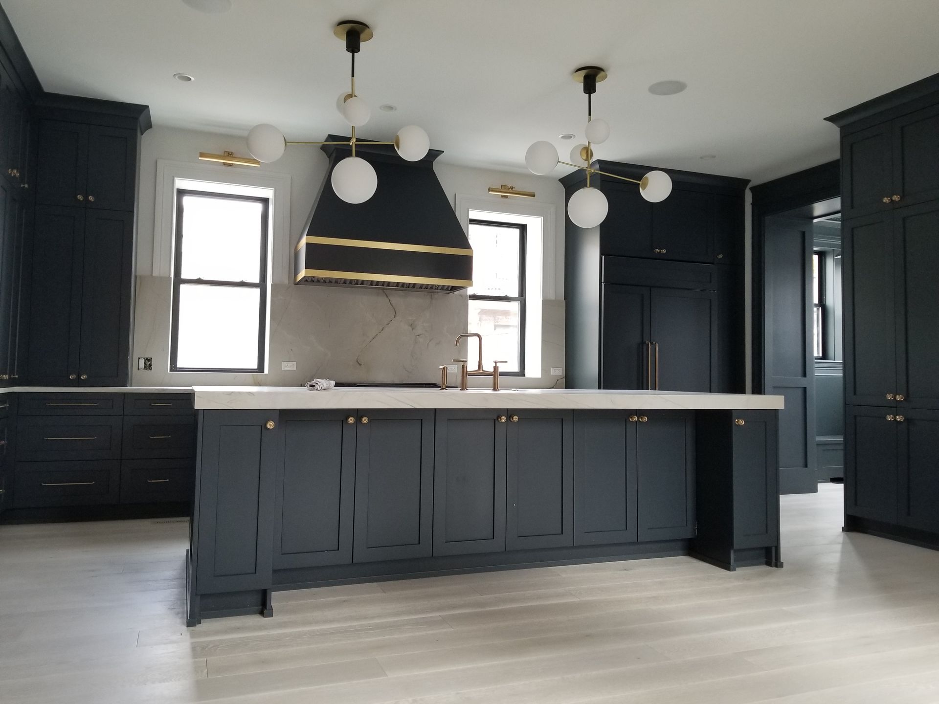 Modern black-and-white kitchen with a large island, marble backsplash, and pendant lights