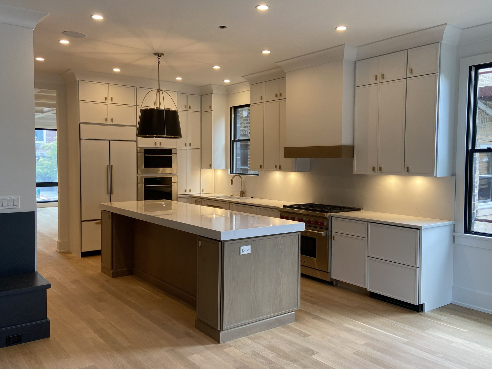 Bright modern kitchen with white cabinets, large island, built-in ovens, and pendant lighting