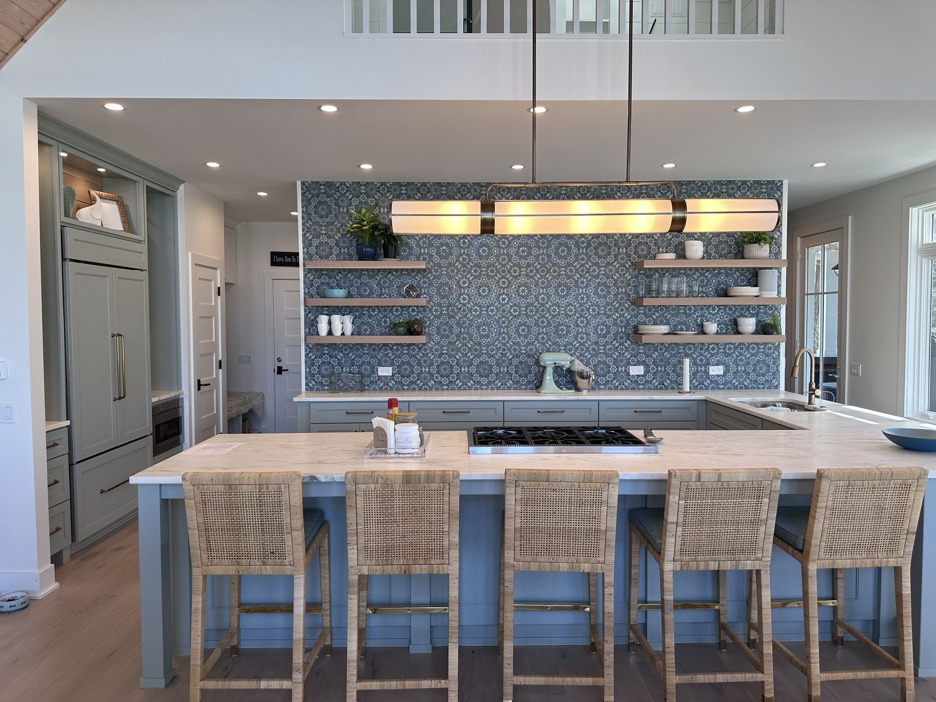 Modern kitchen with white island, wicker stools, mosaic tile backsplash, and stainless appliances