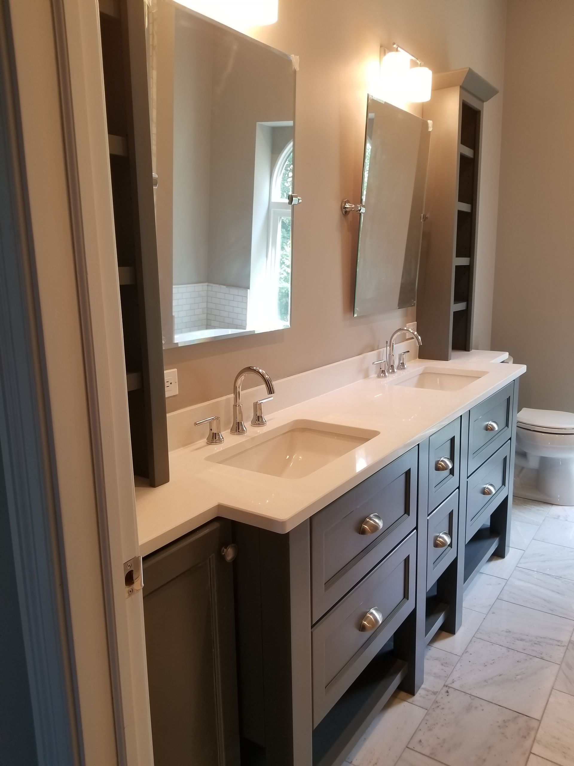 Bathroom with double vanity, large mirrors, and tiled floor in neutral tones
