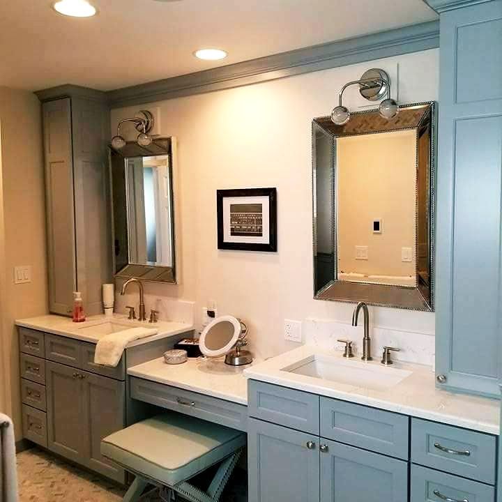 Double vanity bathroom with blue cabinets, two mirrors, sinks, and a central makeup counter.