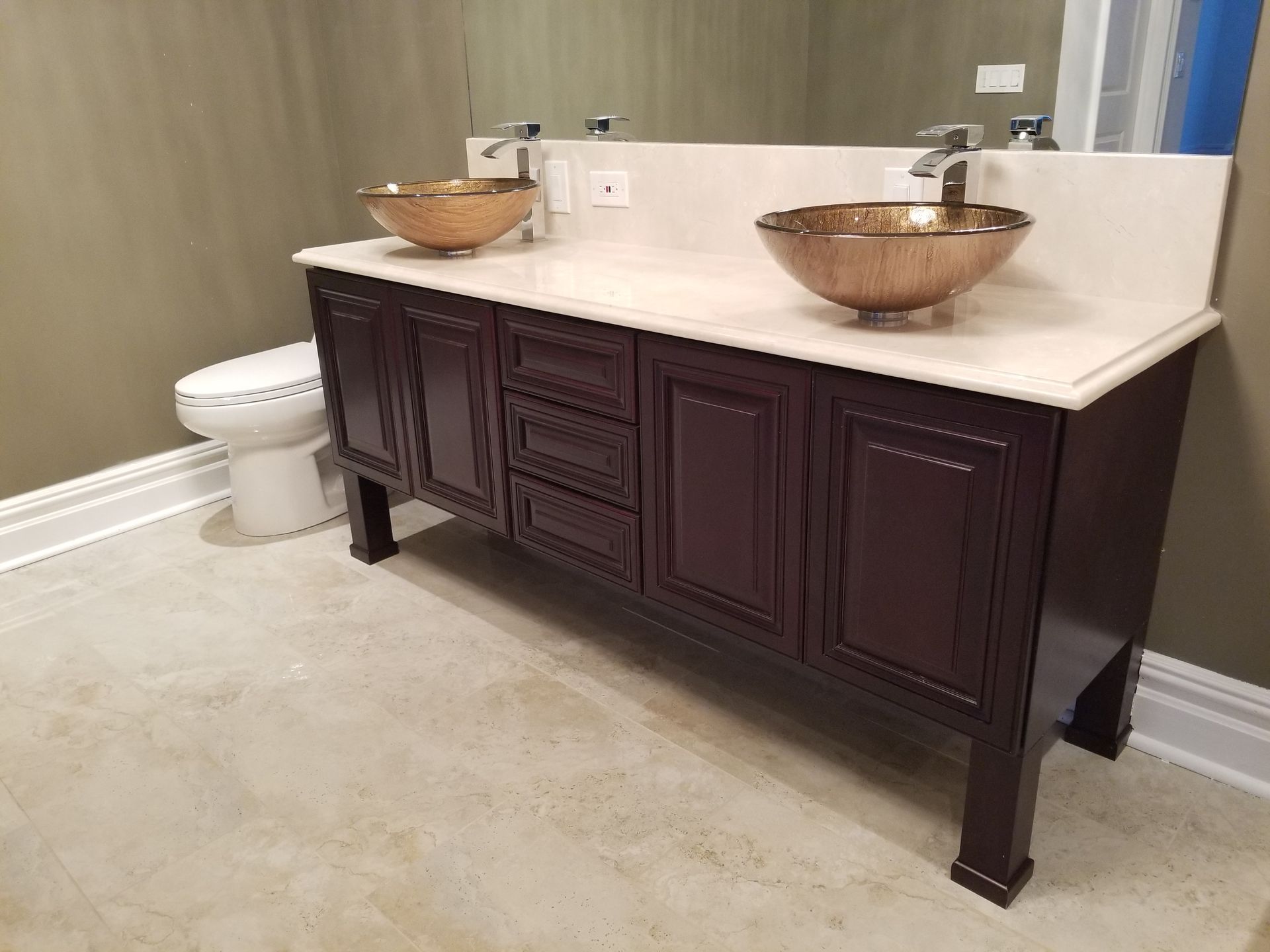Bathroom with dark wood vanity, white countertop, and two copper vessel sinks beside a toilet.