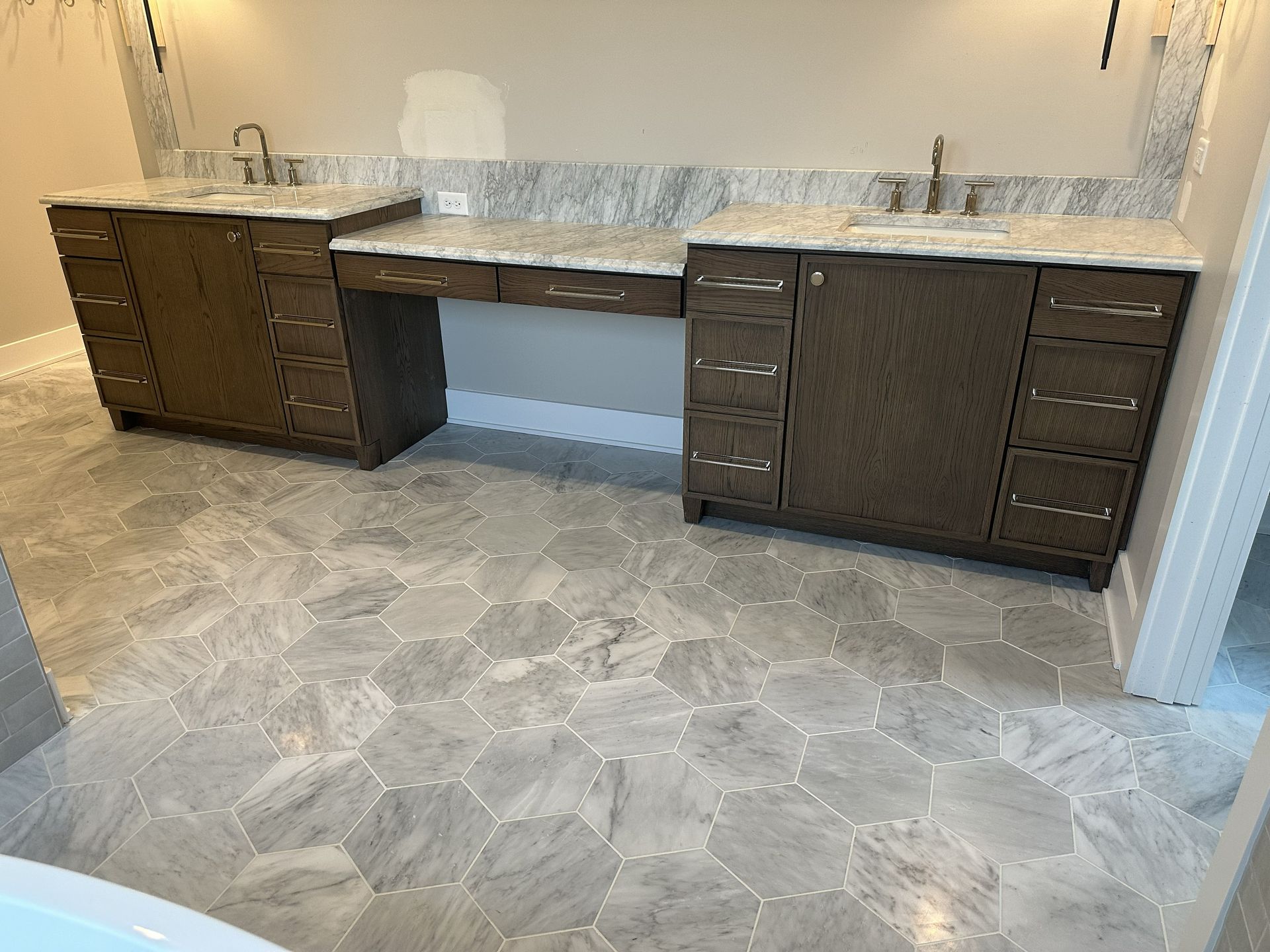 Bathroom vanity with two dark wood cabinets, white countertops, and large gray stone-pattern floor tiles