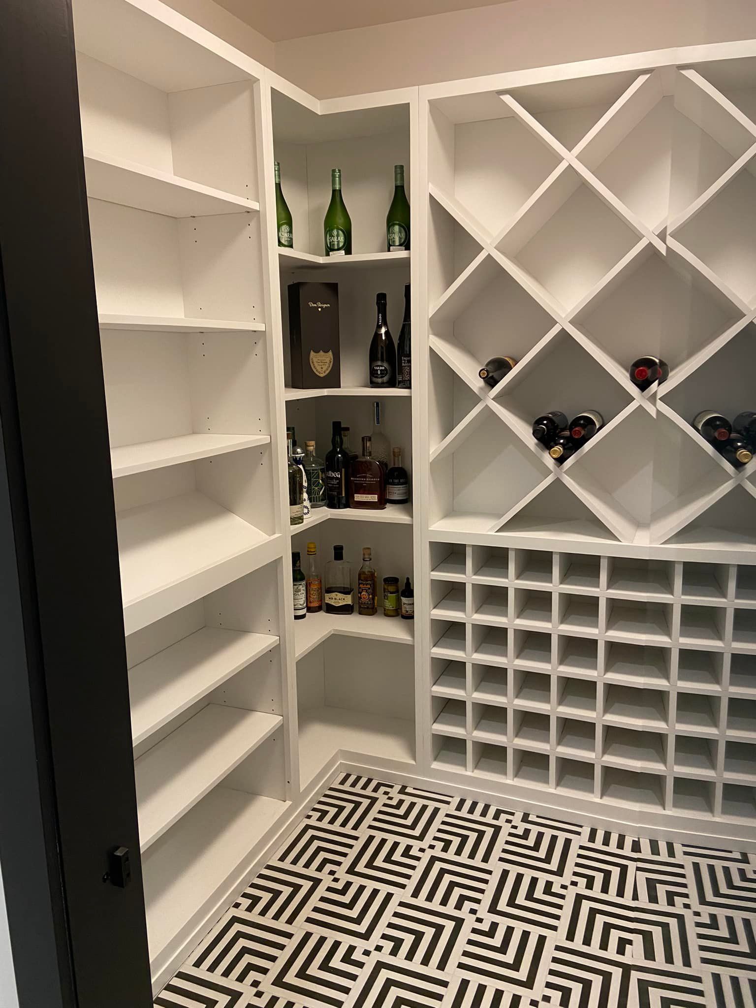 White walk-in wine cellar with shelves, diamond bottle display, and patterned black-and-white floor.