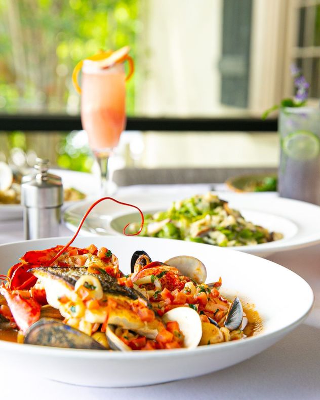 Set table with lobster cioppino and a cocktail