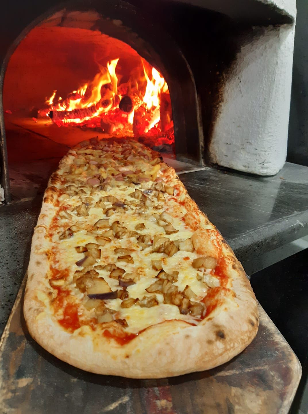 Una pizza viene cotta nel forno a legna.