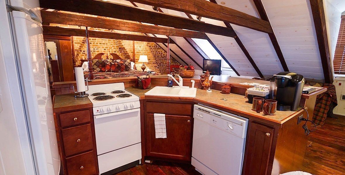 Cozy loft kitchen with wooden cabinets, white stove, and slanted ceiling beams