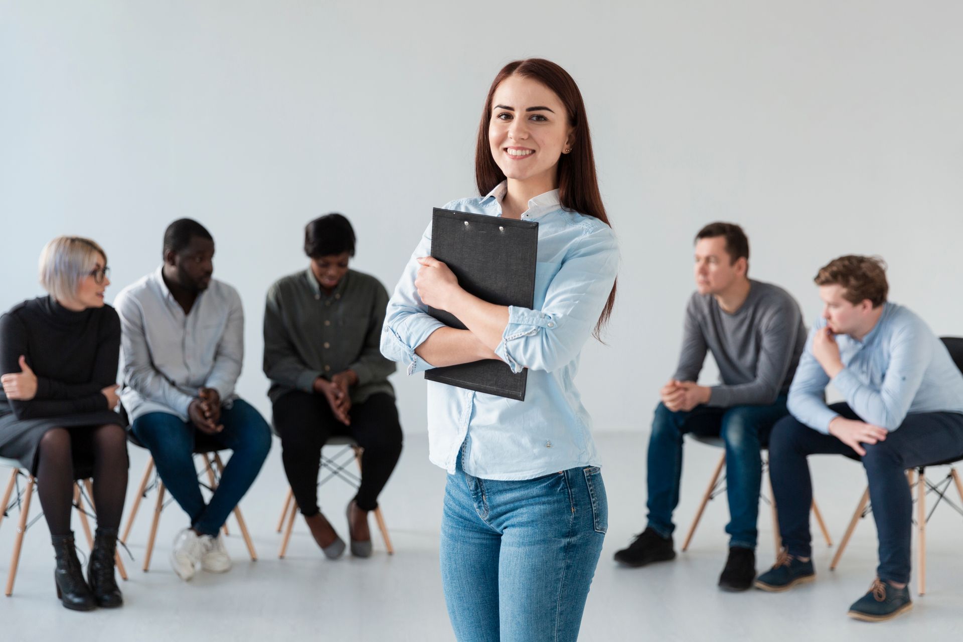 En primer plano, una persona aparece sonriendo y sosteniendo un portapapeles negro