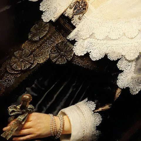 A detail of a portrait of Maria Trip by Rembrandt van Rijn showing a sleeve and neckerchief made of the finest lace and a pearl bracelet