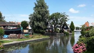 Uitzicht op een gracht met in de verte de typische groene houten huisjes van Edam vlakbij Amsterdam