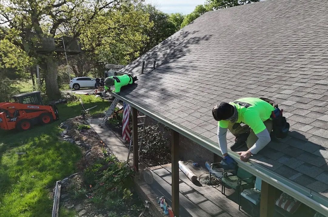 Two men are working on the roof of a house | roofing repair in springfield mo