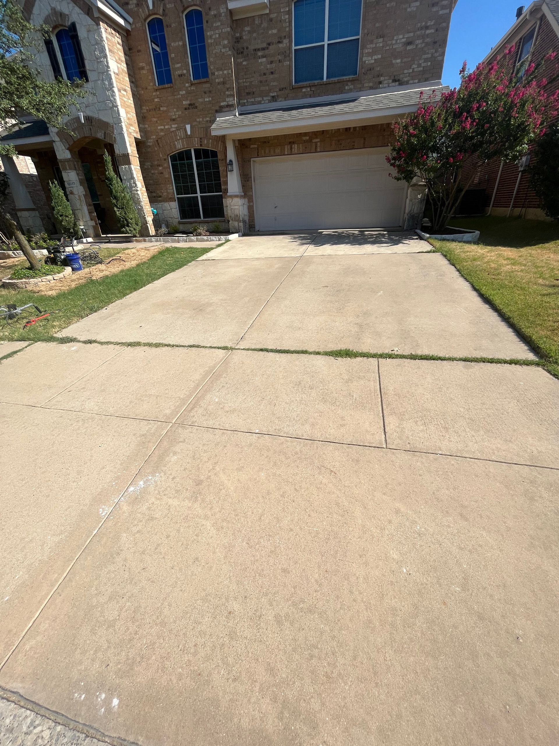 A concrete driveway leading to a large brick house.