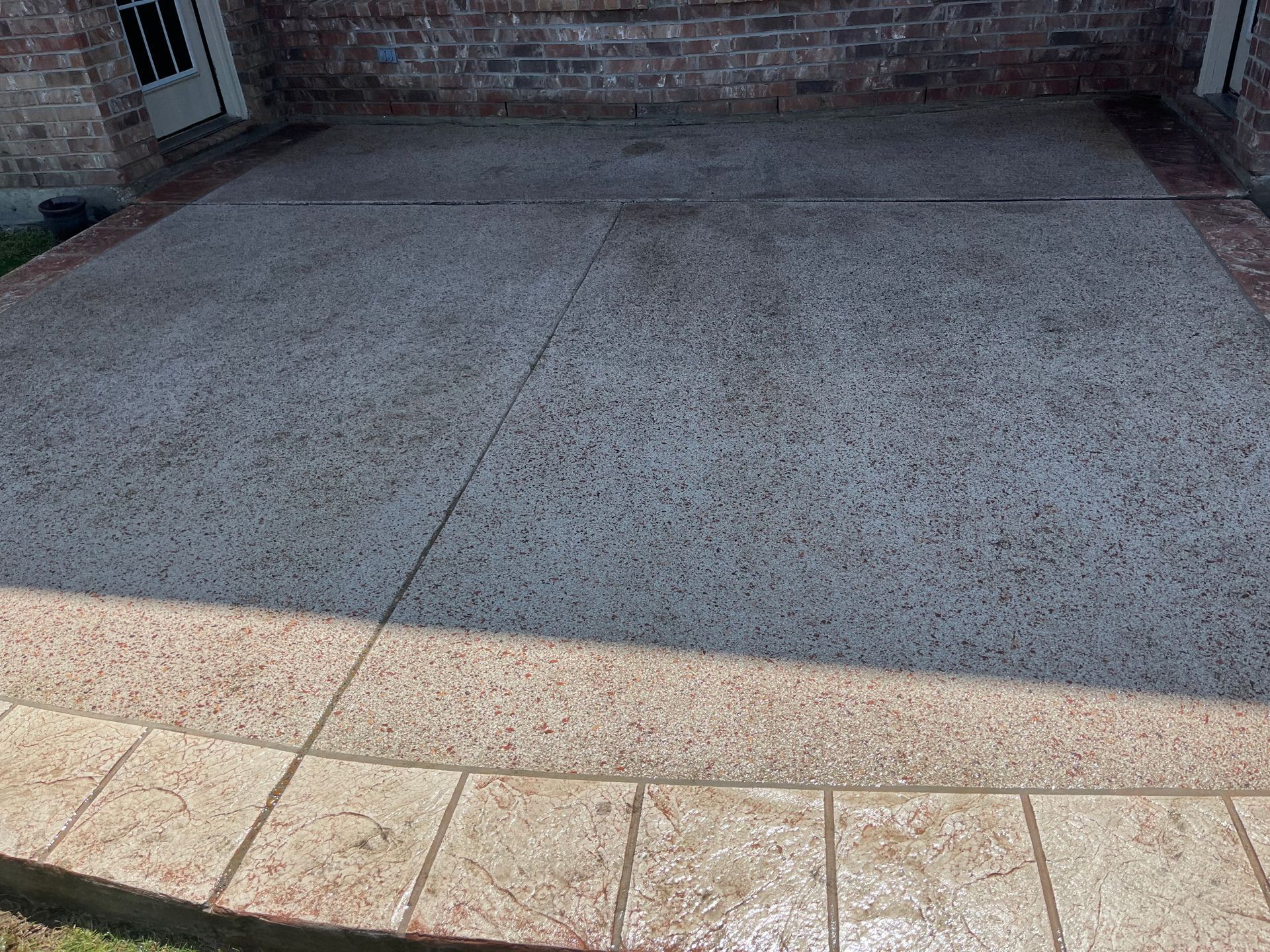 A concrete driveway with a brick wall in the background.