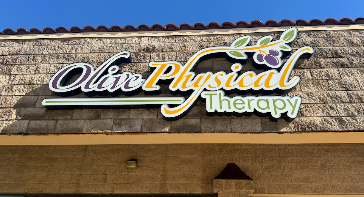 A sign for olive physical therapy is on a brick building