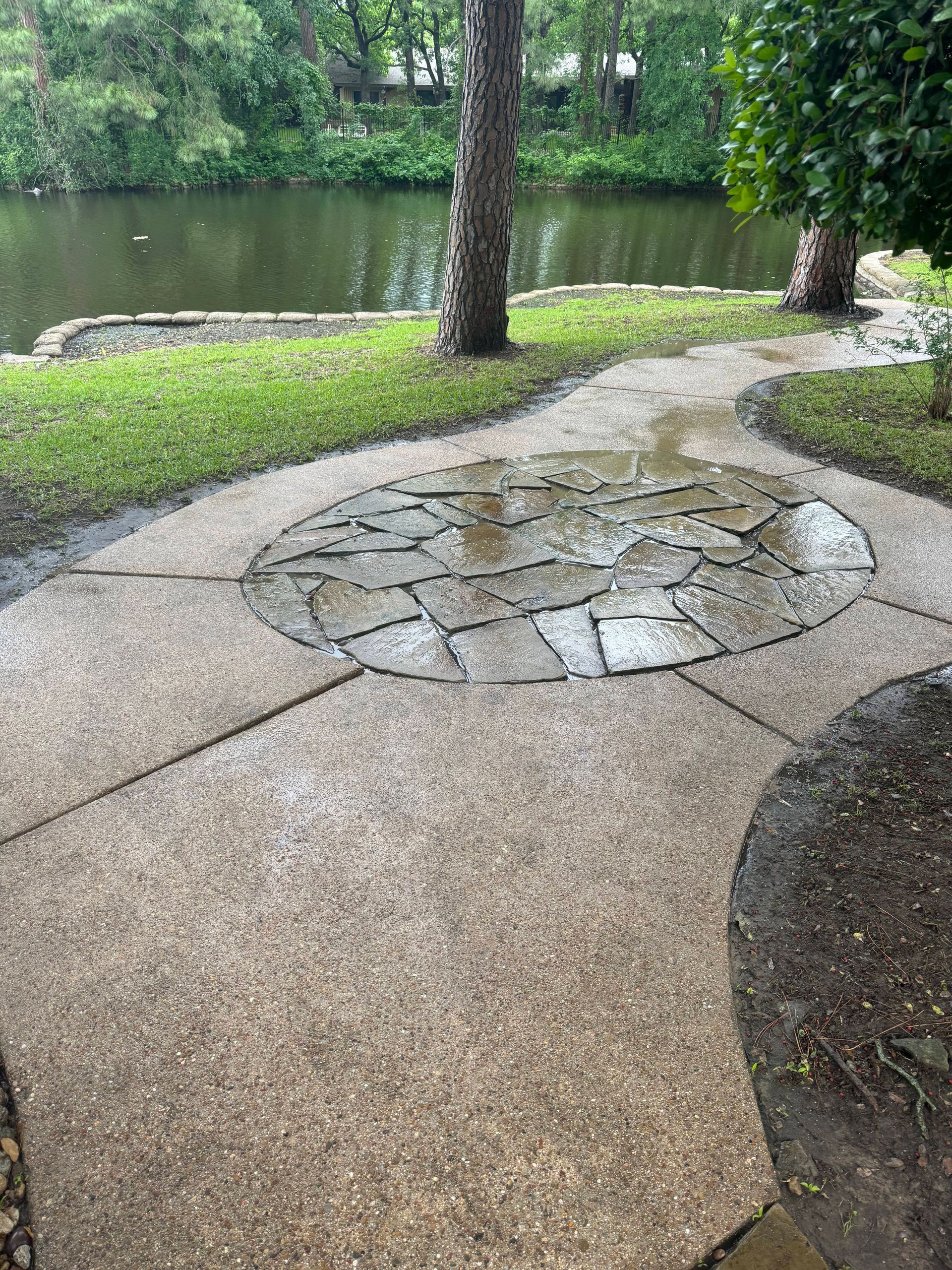 A patio with a stone circle in the middle and a river in the background.