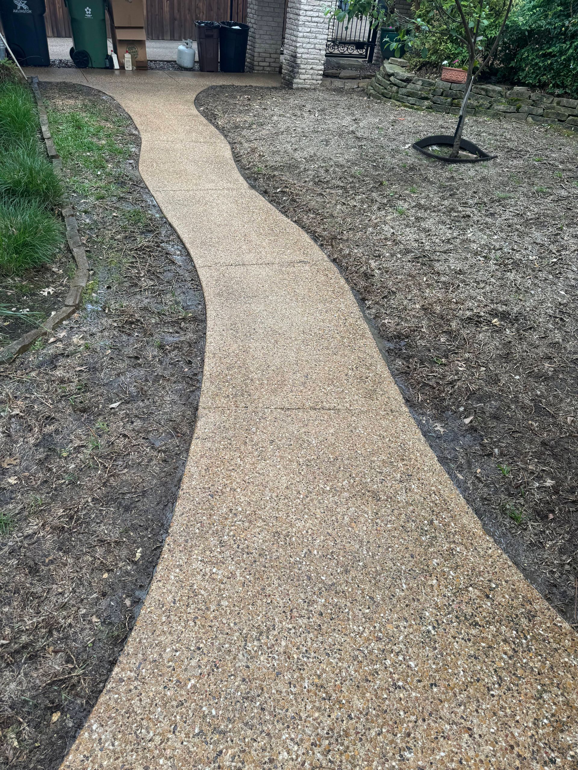 A walkway in a backyard surrounded by gravel and grass.