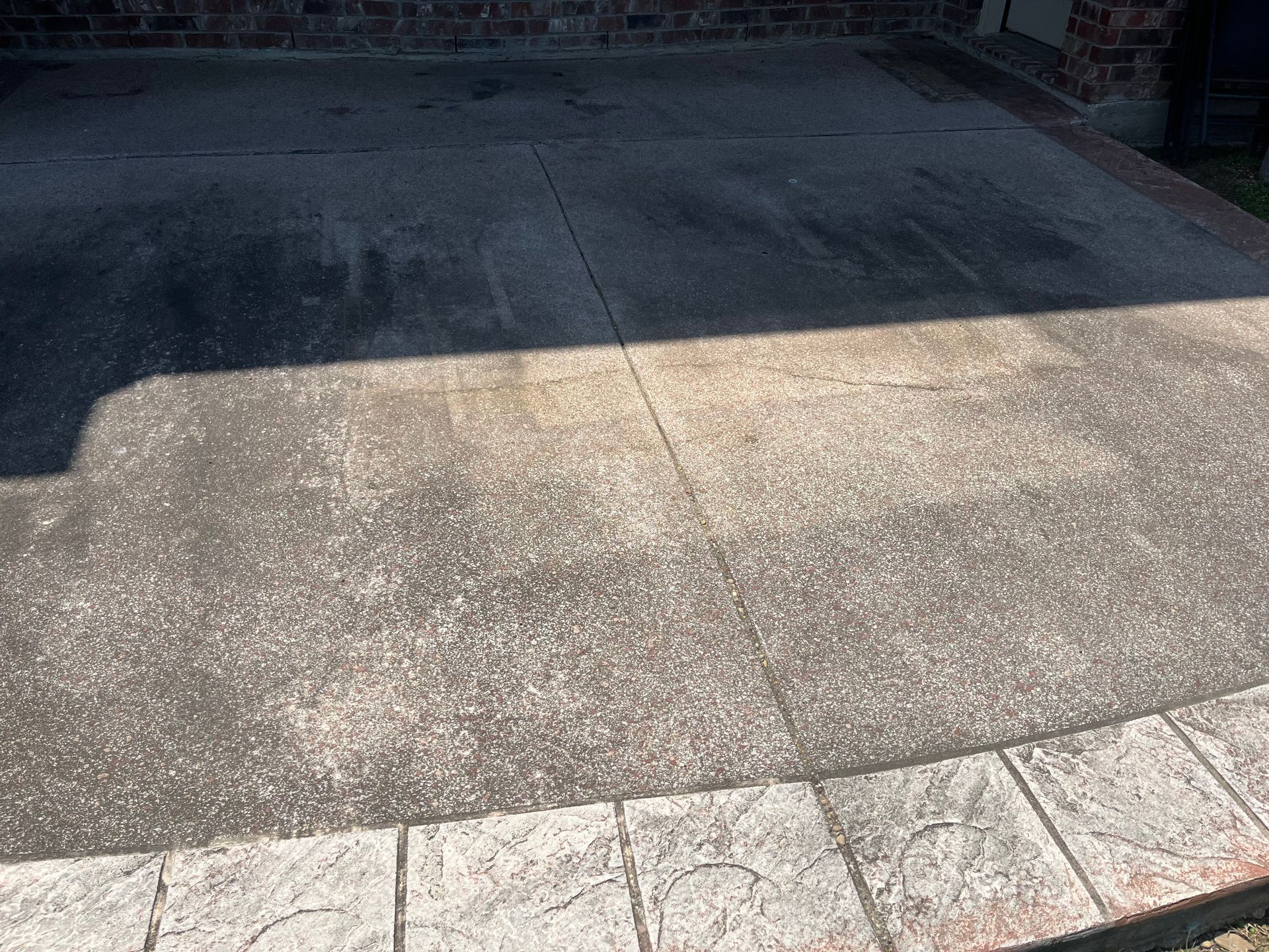 A concrete driveway with steps leading up to it and a brick wall in the background.