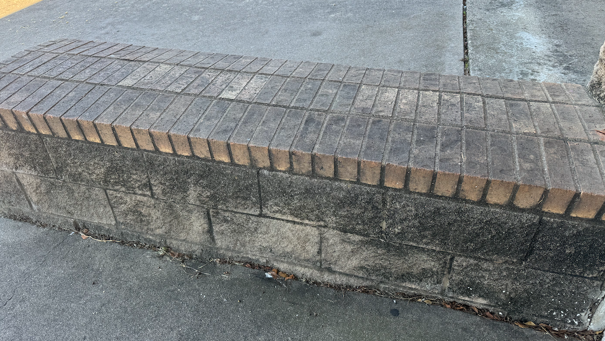 A brick bench is sitting on top of a brick wall.