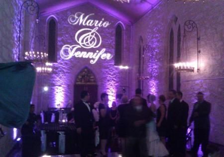 Purple-lit wedding reception with guests mingling under a “Mario & Jennifer” sign