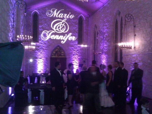 Purple-lit wedding hall with guests gathered under a “Mario & Jennifer” sign