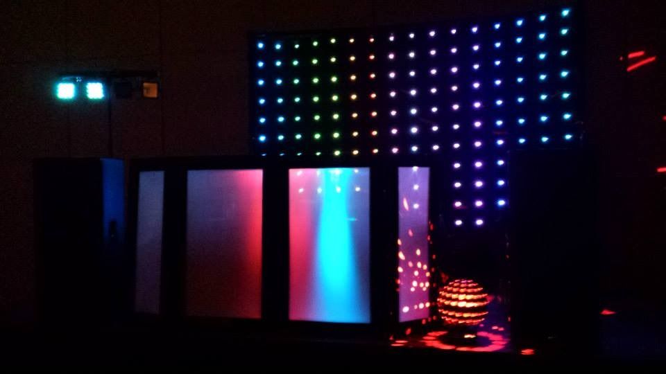 Dark room with colorful LED wall panels and glowing lights, creating a neon display.