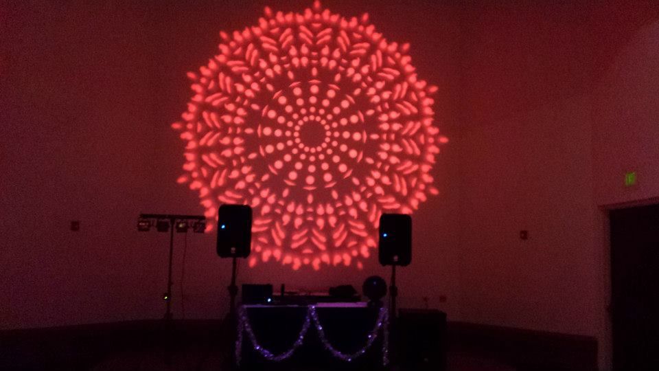 Red floral light projection on a stage with speakers and string lights in a dark room
