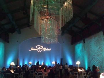 Elegant banquet hall with blue lighting, chandeliers, and guests seated at tables during an event