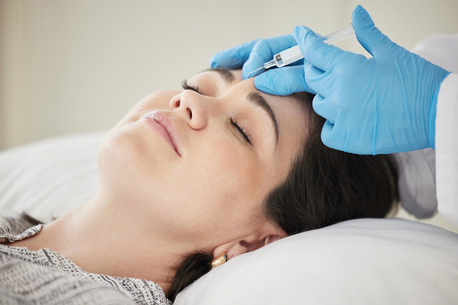 Gloved hands placing a cold compress on a resting person’s forehead