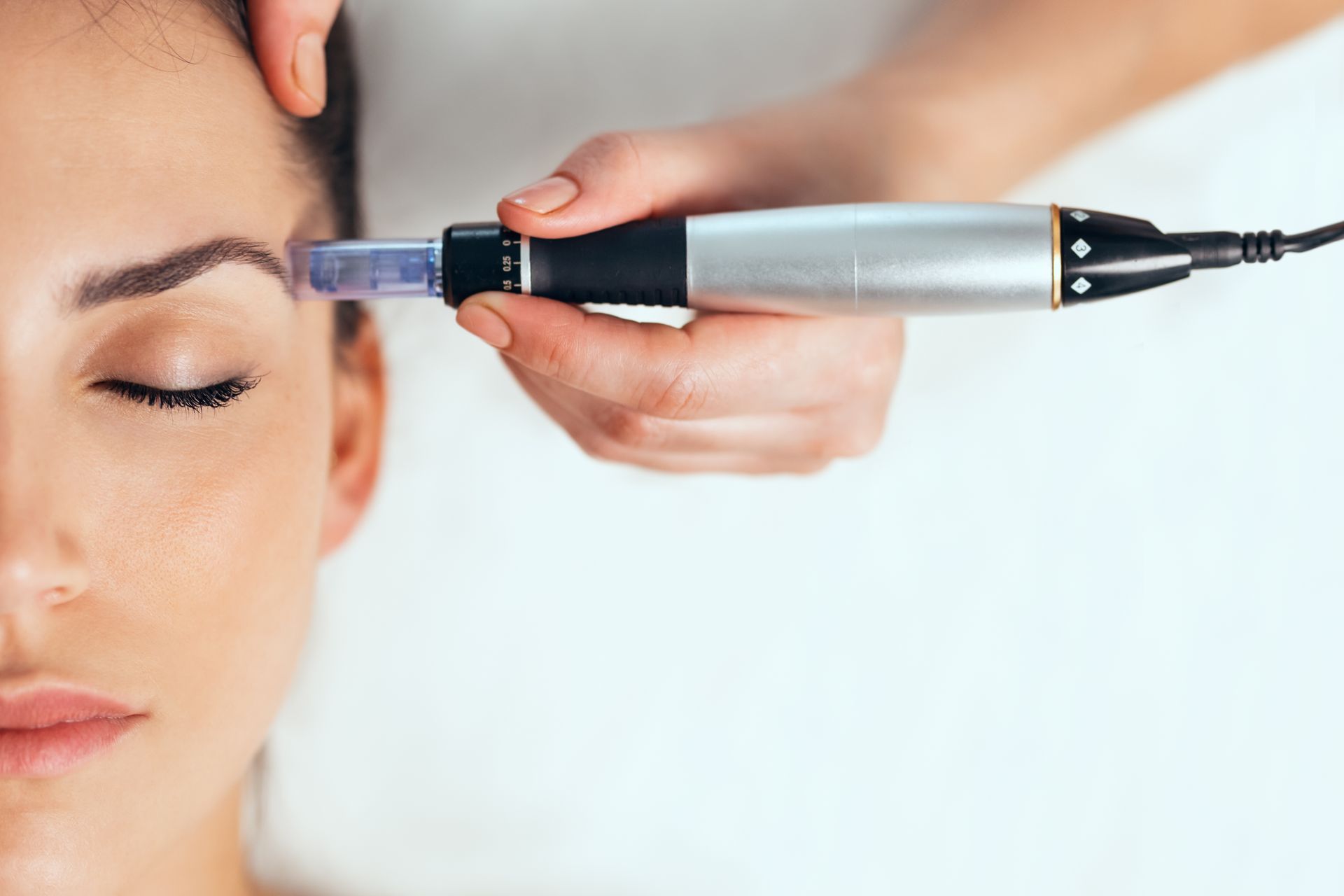 Cosmetic treatment being applied near a woman's eyebrow with a handheld device