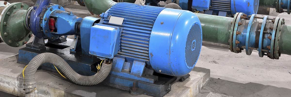 Blue industrial pump connected to large metal pipes in a utility setting