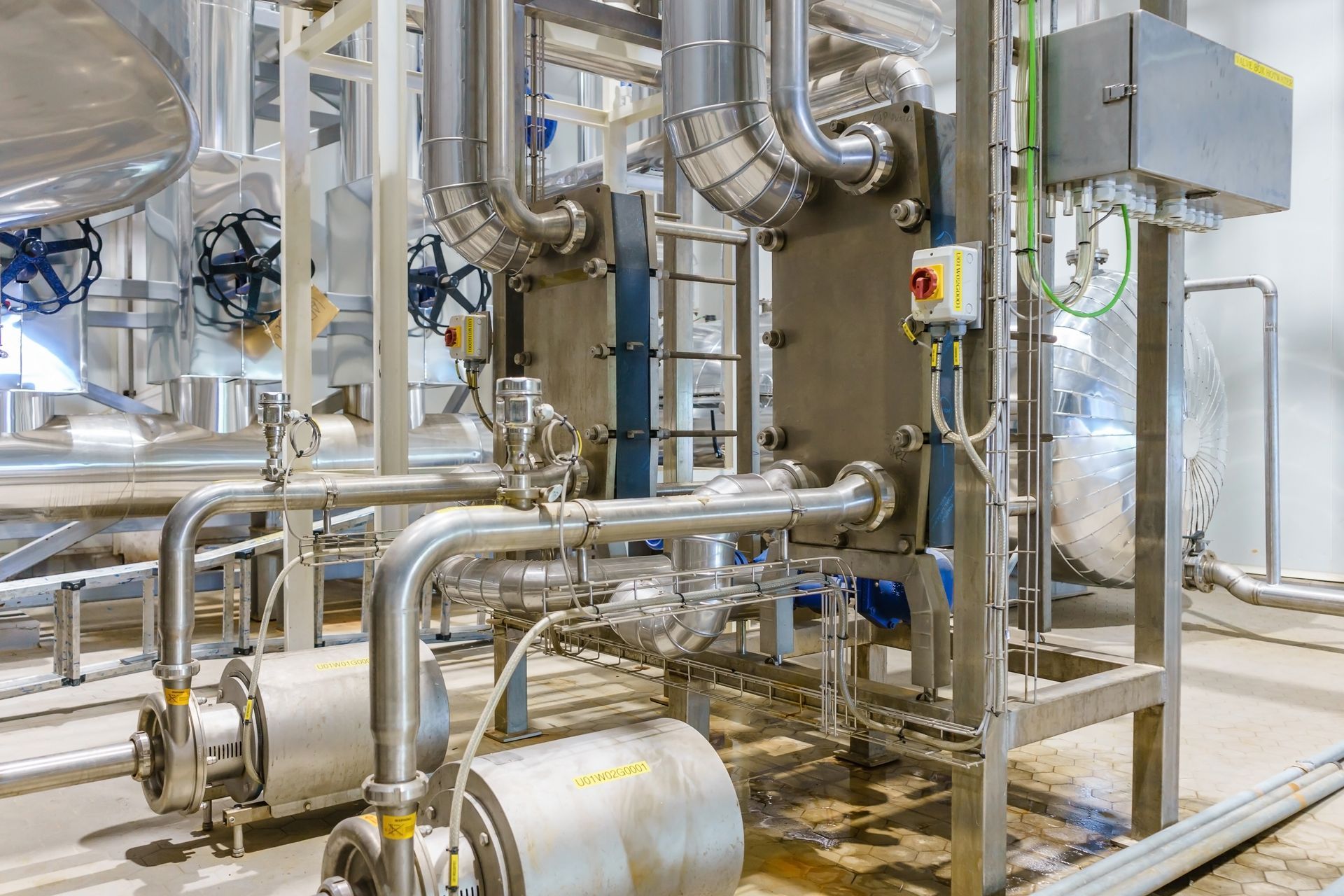 Stainless steel industrial pipes and machinery in a bright factory room