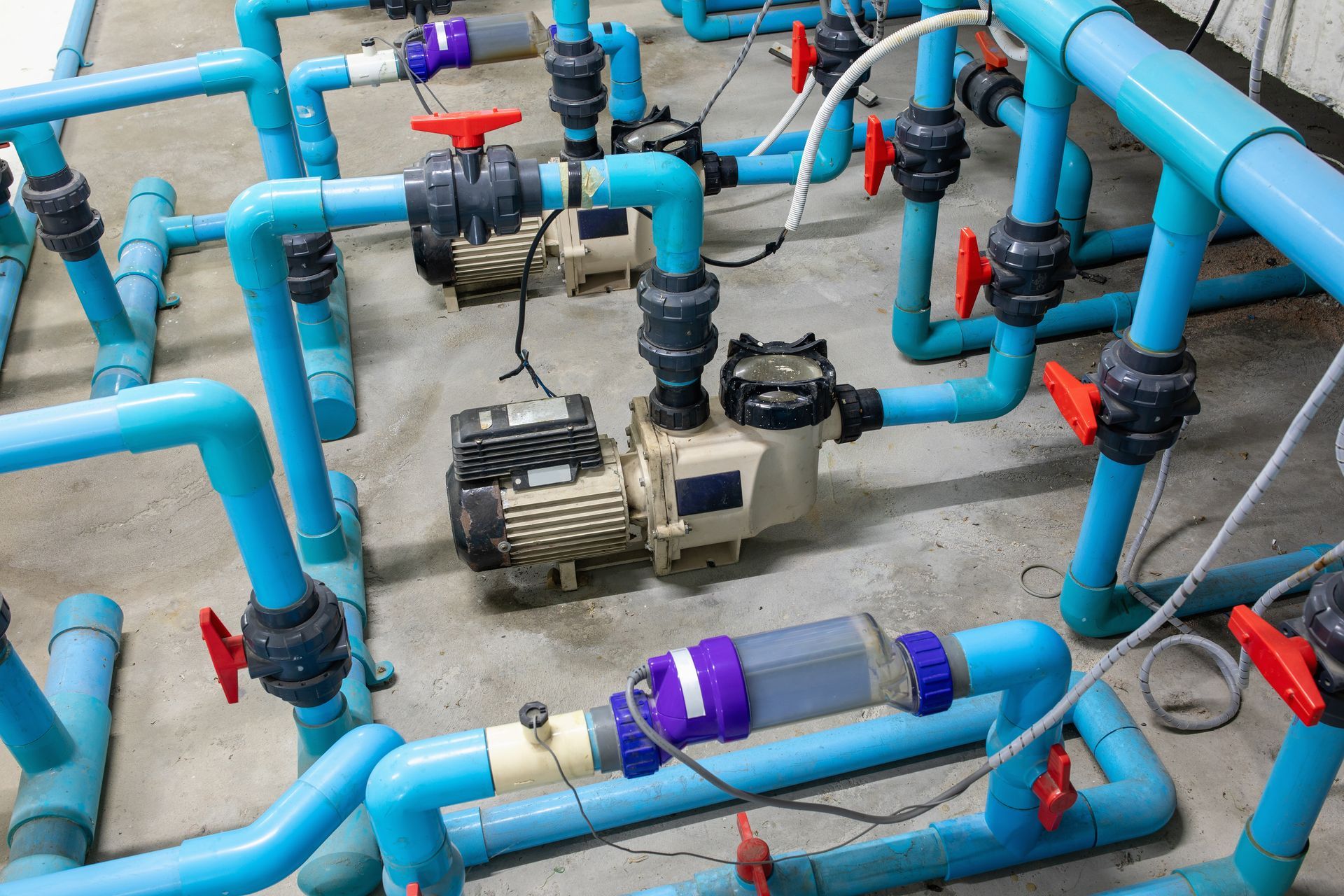 Blue pipes and valves around a pump on an industrial floor